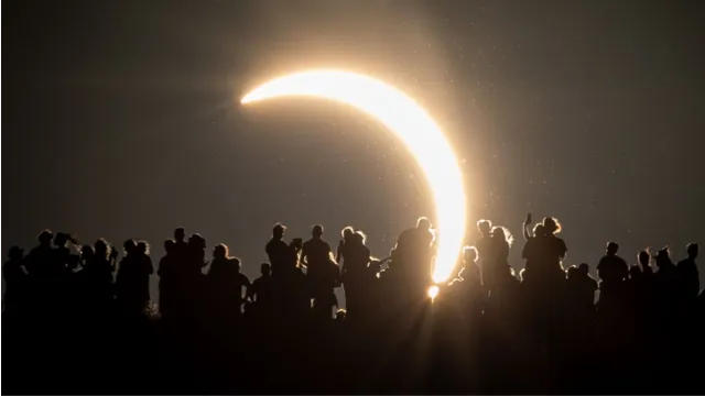 Público assiste ao eclipse solar parcial em Glastonbury Tor, 2026.